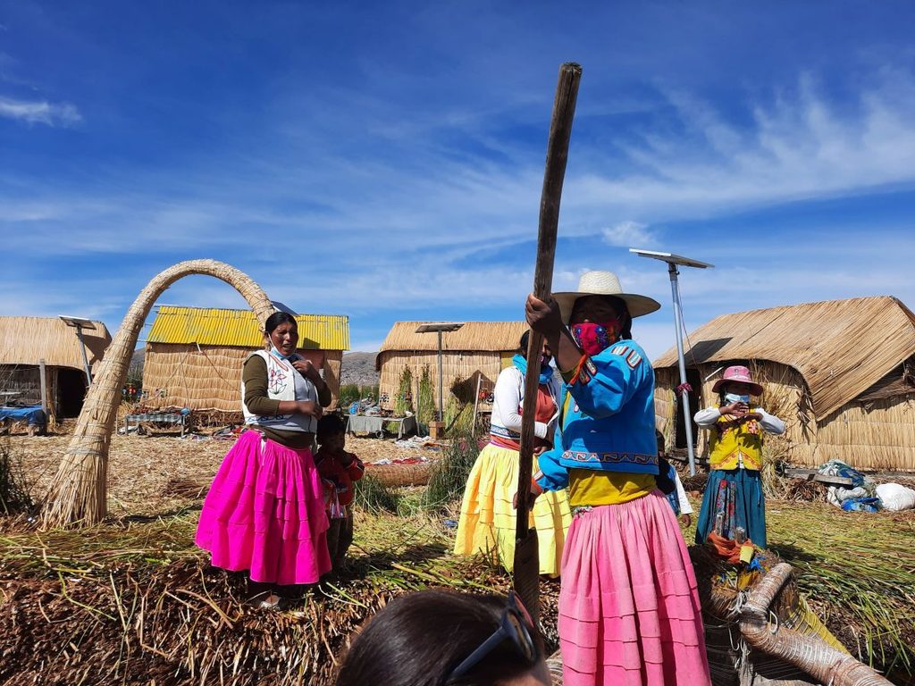 Three local women working by Lake Titicaca in Peru, surrounded by the Andean landscape.