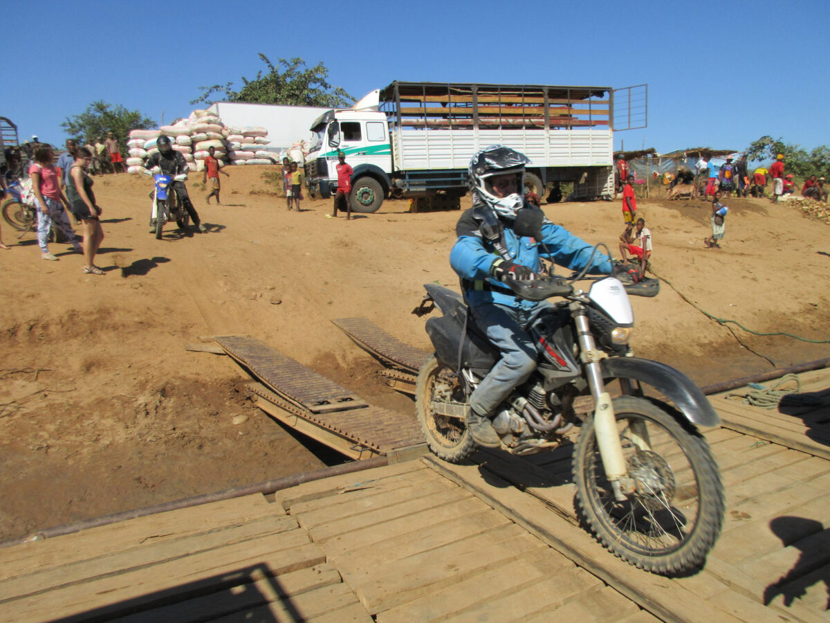 Motorradfahrer überquert eine Holzbrücke auf einer Motorradreise durch Afrika