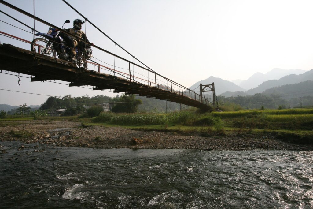 Motorradfahrer überquert eine Brücke auf einer Motorradreise durch Vietnam